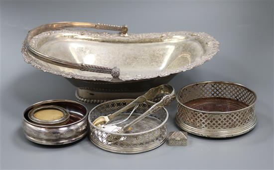 A George III silver wine coaster, London, 1768, two later silver coasters, a photo frame, tongs, pill box and plated bread basket.